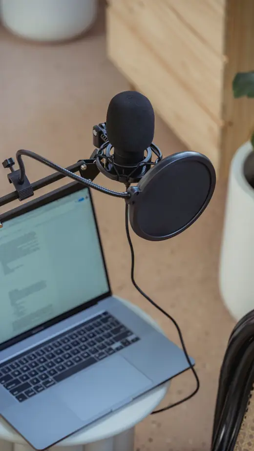A laptop and a studio microphone on a desk.