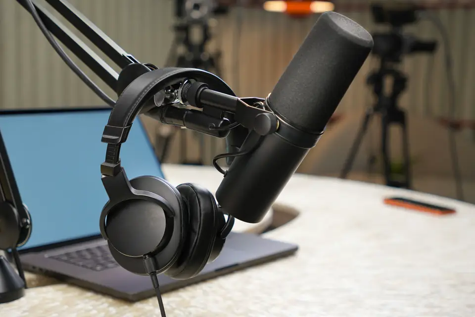 A podcast microphone, headphones and a phone on a desk.